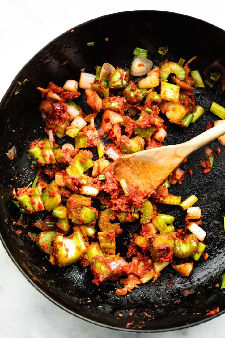 tomato paste being added to celery and onions for tomato crab bisque