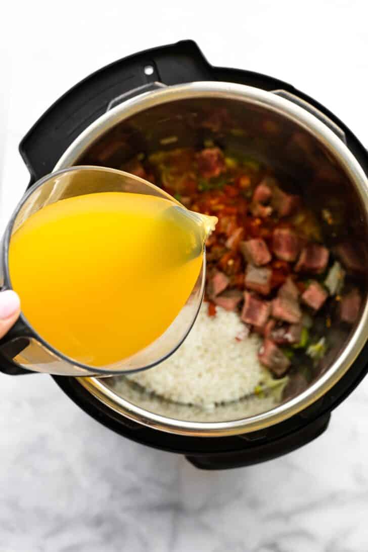 Pouring broth into a pressure cooker for soup.