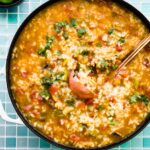 Overhead photo of a copper ladle in a pot of Mexican steak soup.