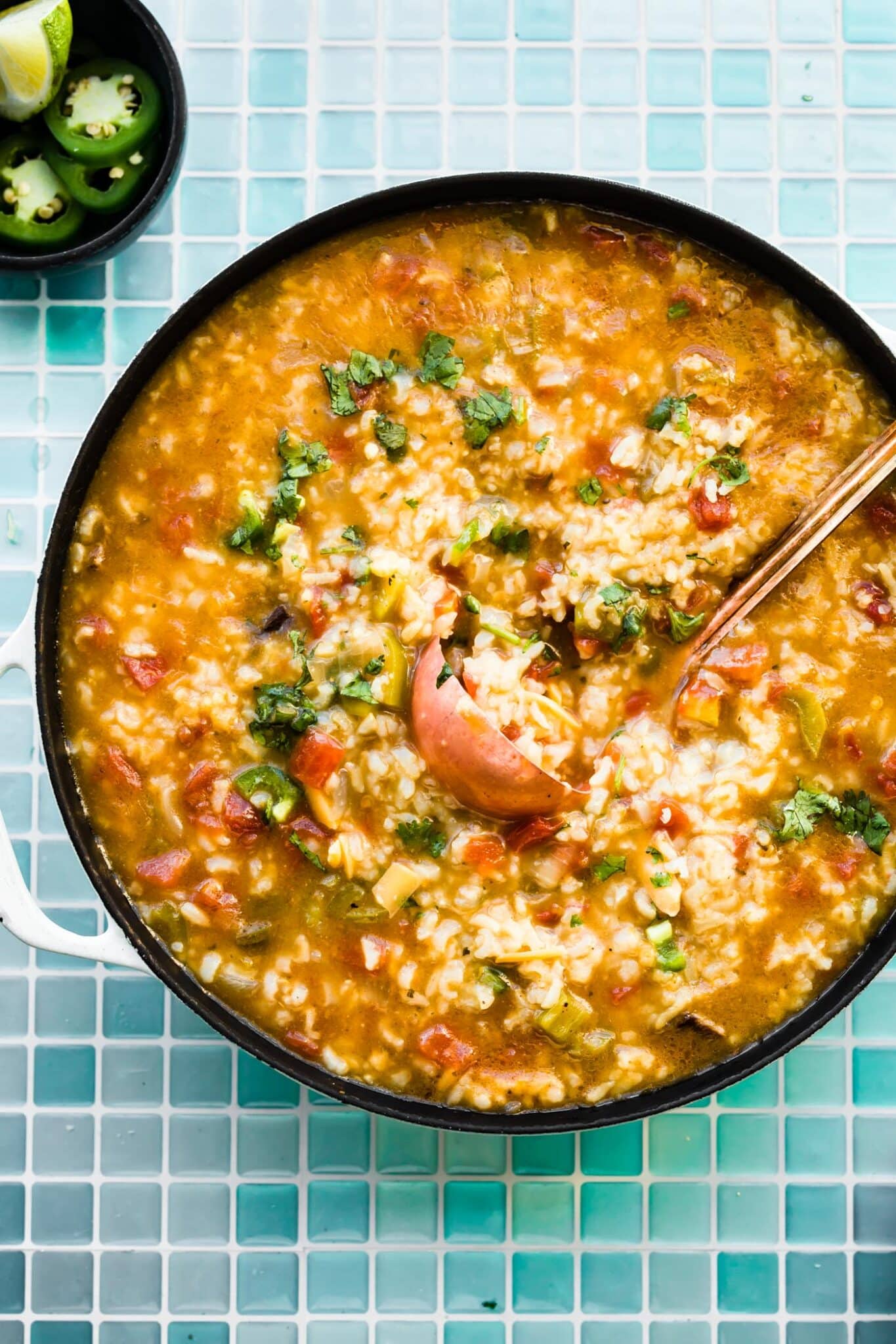 Overhead photo of a copper ladle in a pot of Mexican steak soup.