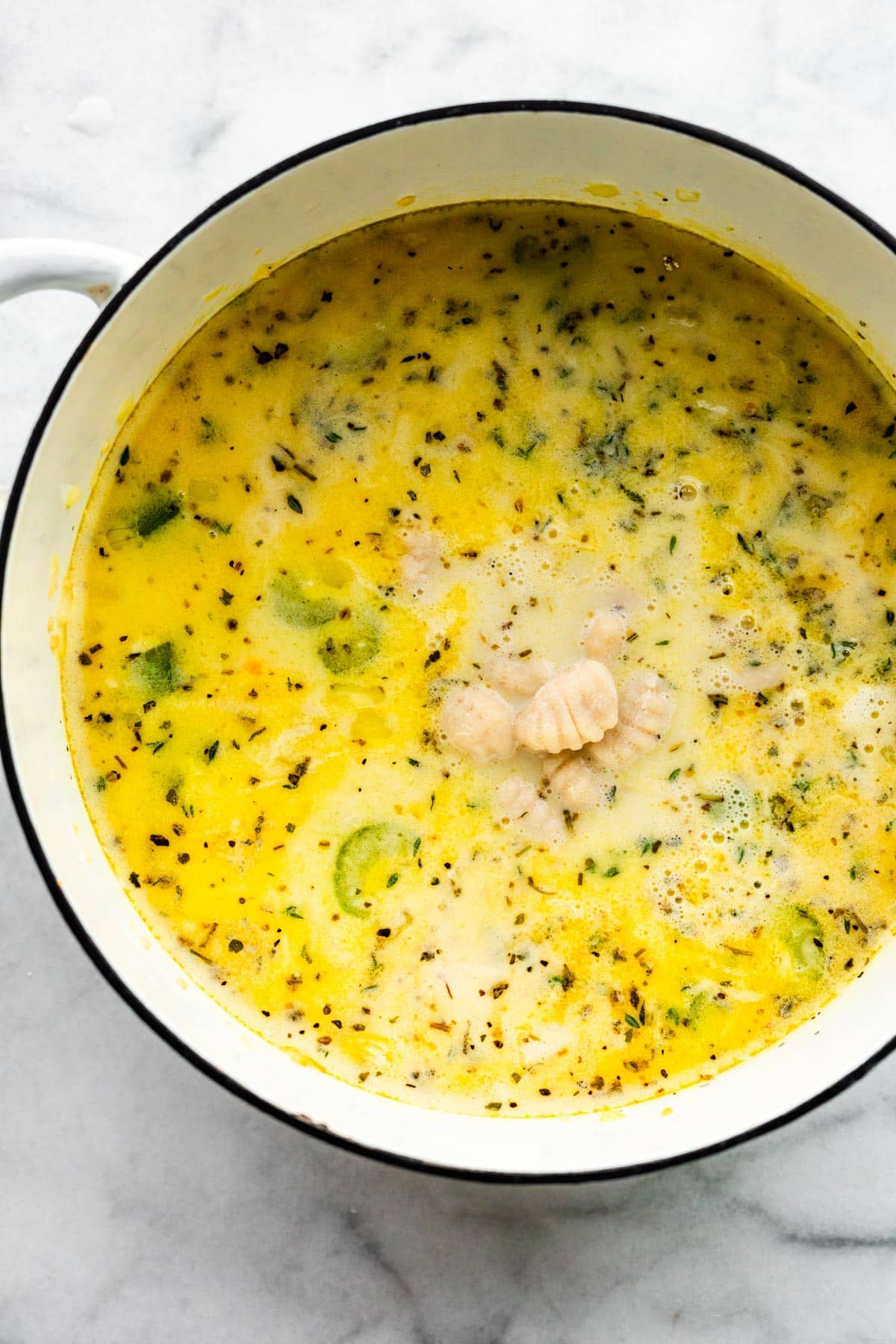 Uncooked gluten free gnocchi in a pot of soup ready to be cooked.