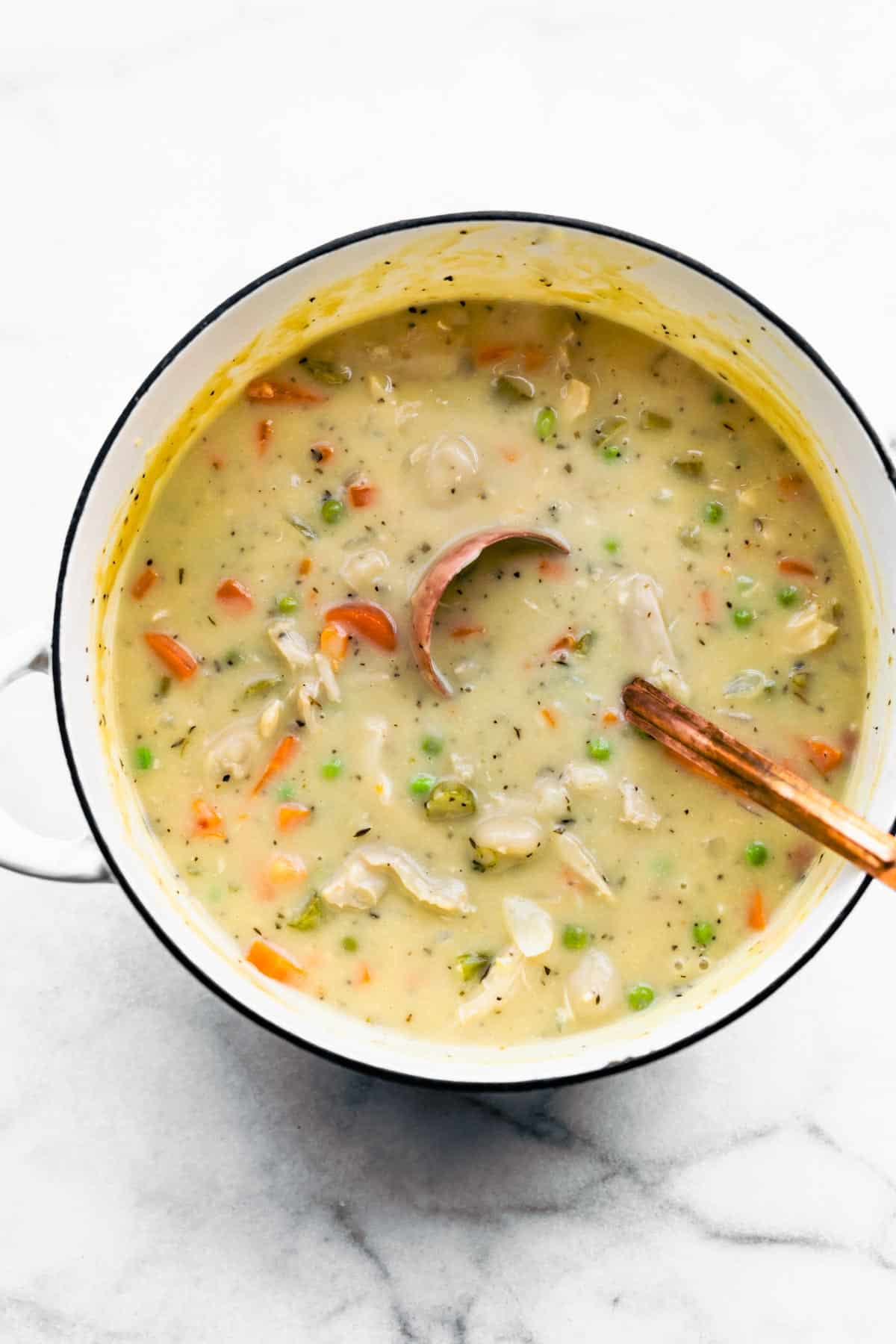 A copper ladle in a pot of dairy free leftover turkey and gnocchi soup.