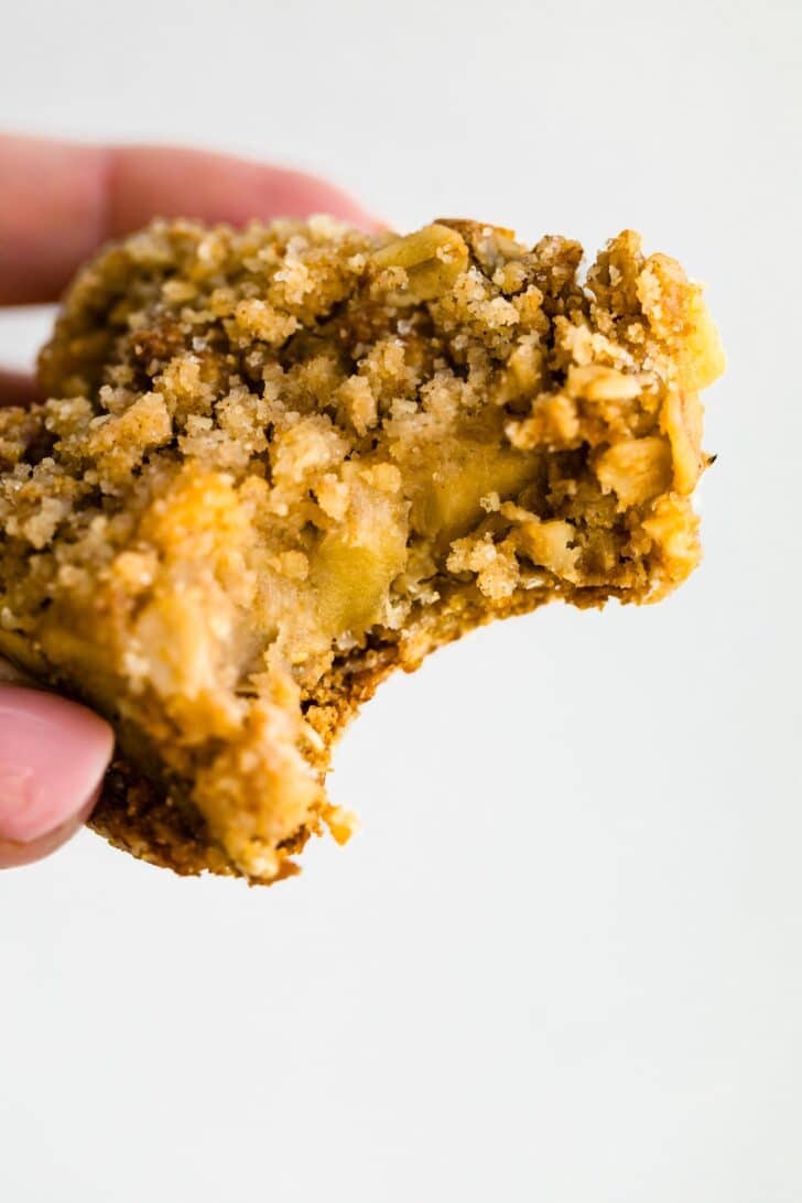 Bite taken out of a gluten-free apple crisp bar showing soft apple filling and crunchy topping.