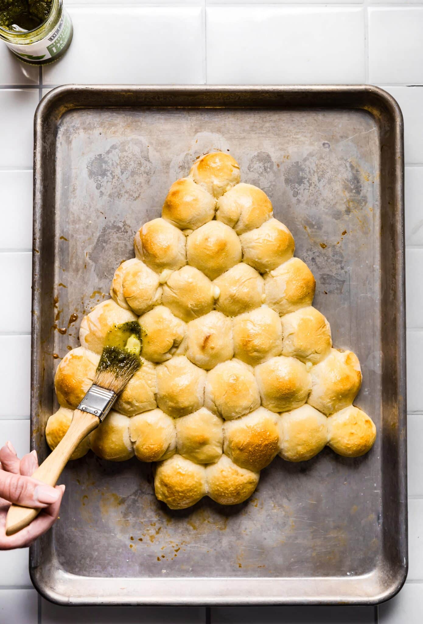 Brushing pesto on baked gluten free Christmas tree pull apart bread.