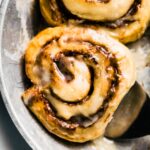 silver pan/plate with gooey gluten free cinnamon roll and serving spatula underneath