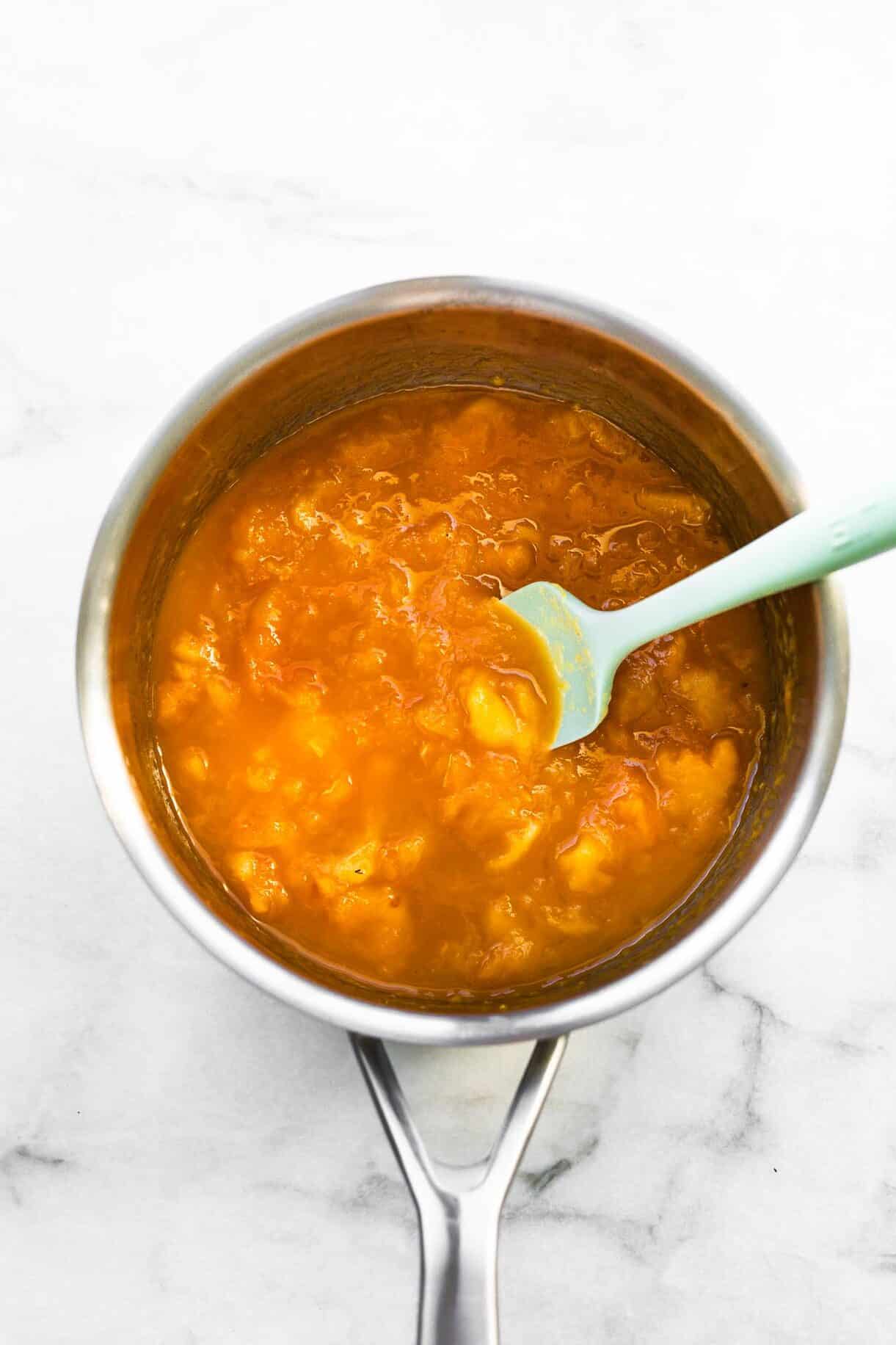 apricot pie preserves in a pot with a blue spatula