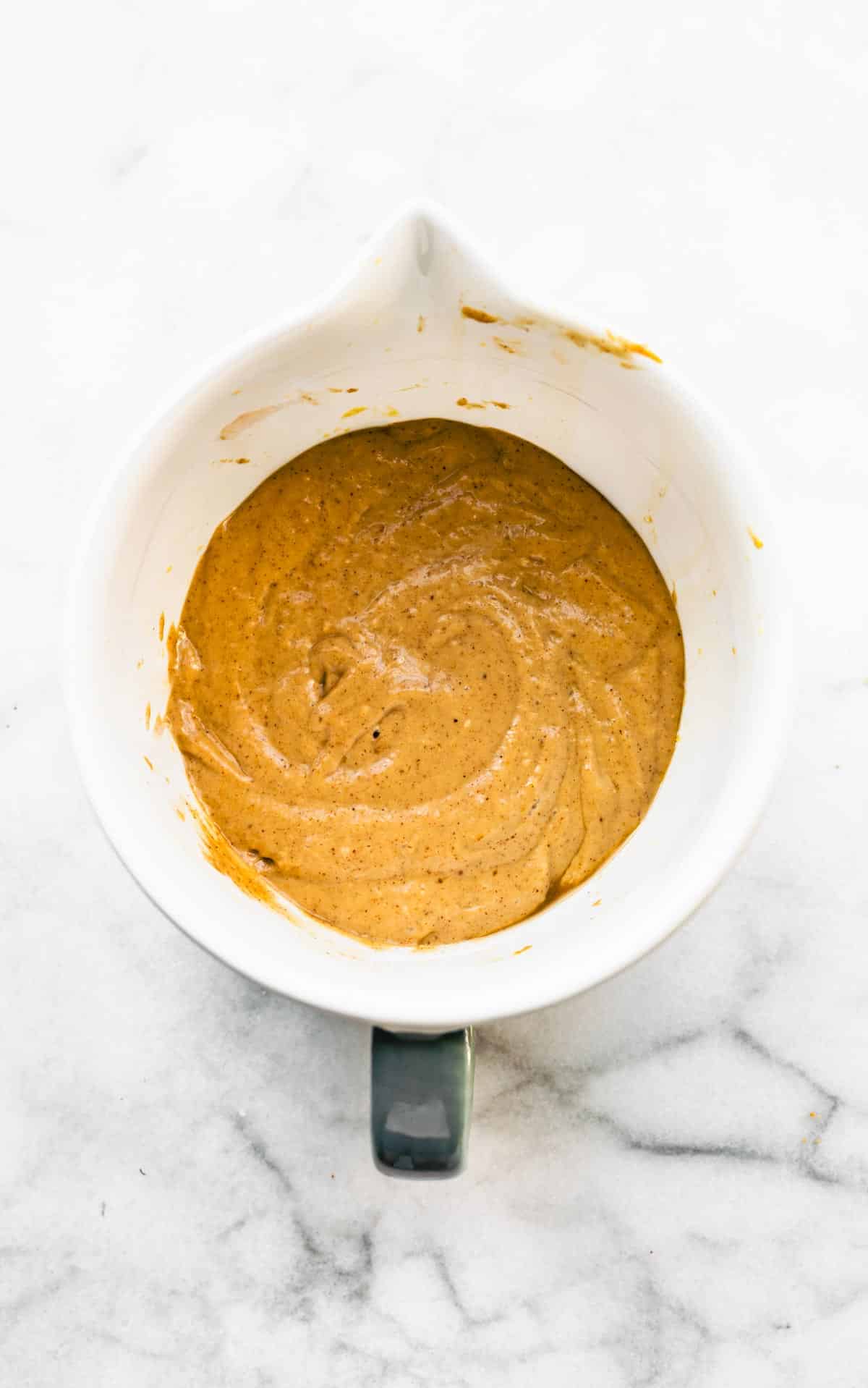 Peanut butter banana muffin batter in a white mixing bowl.