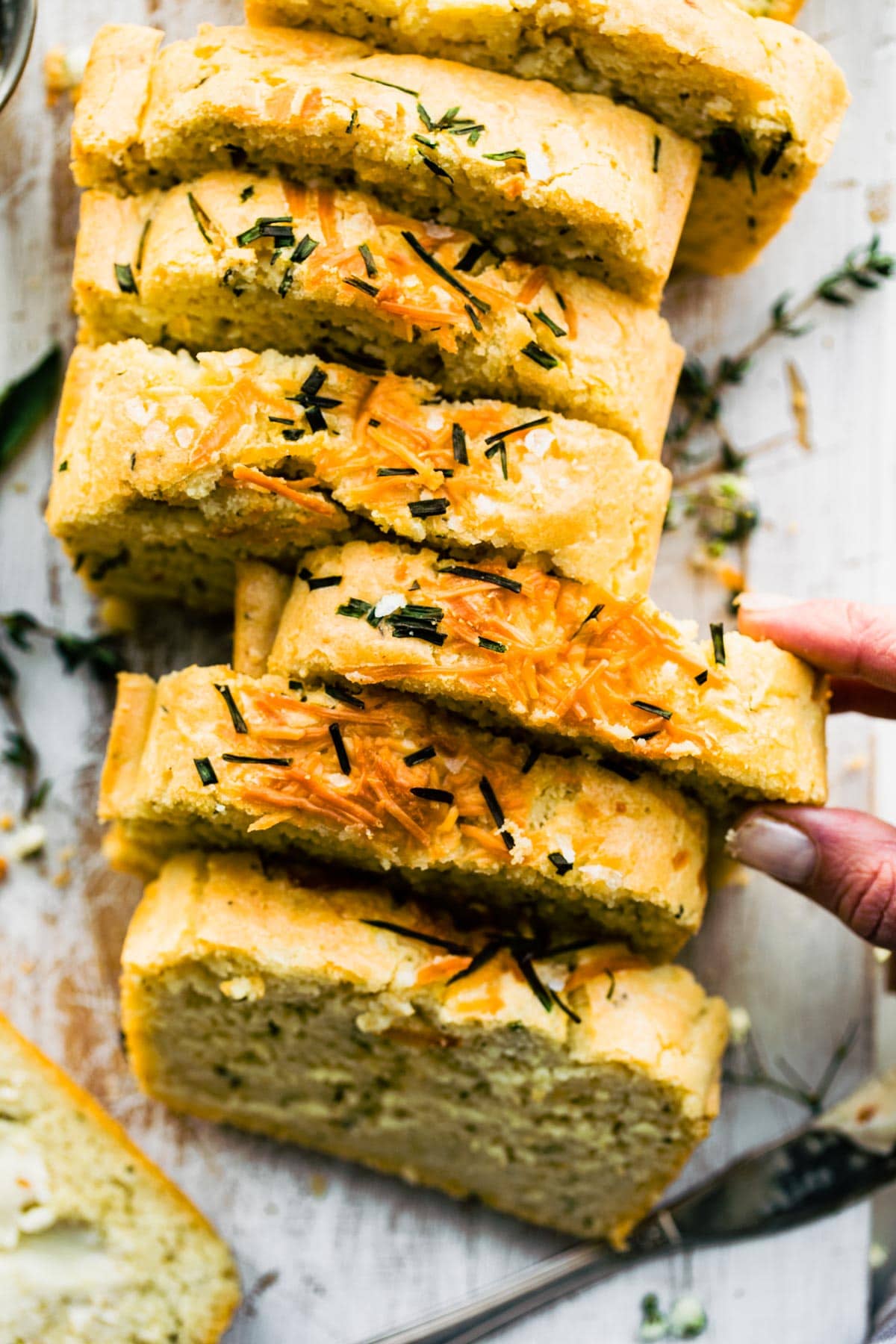 A woman's hand taking a thick slice from homemade loaf of gluten free potato bread.