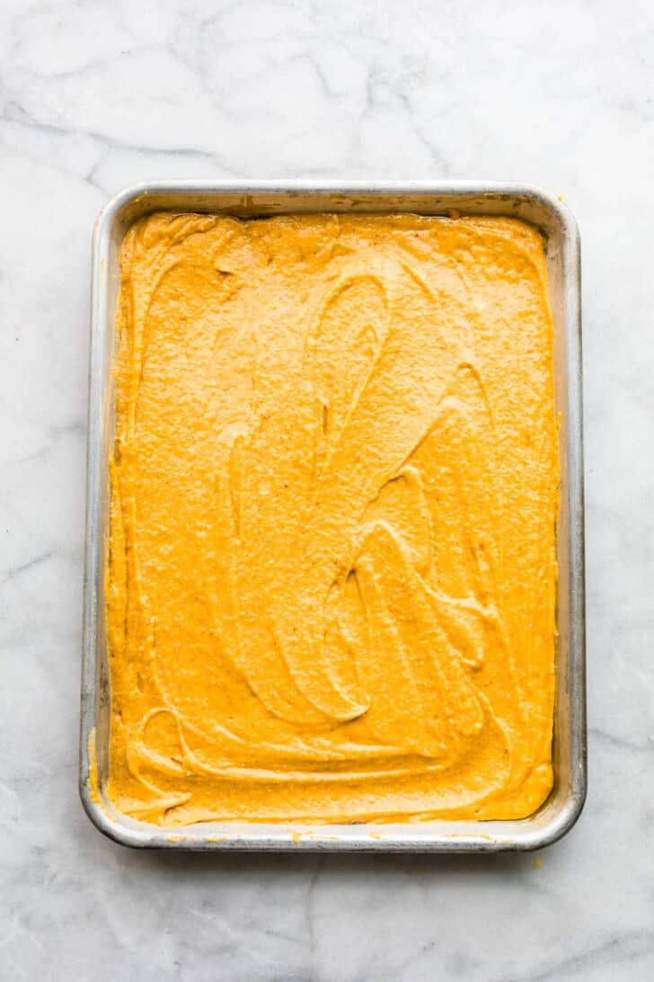 unbaked pumpkin bar batter spread on a sheet pan.