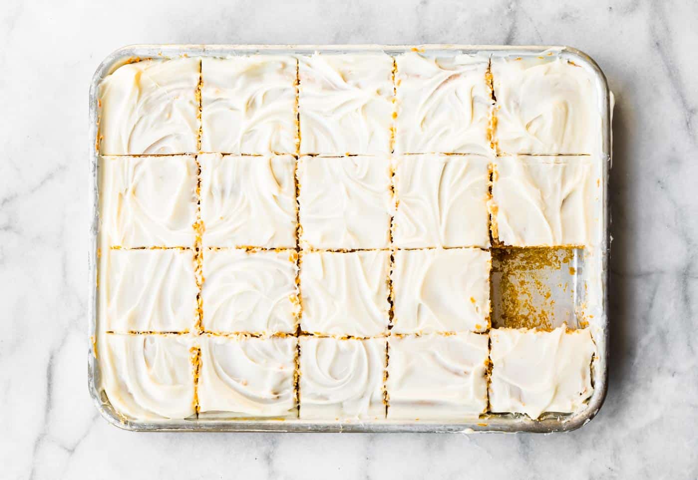 baked and frosted gluten free pumpkin bars  on a sheet pan, sliced into squares