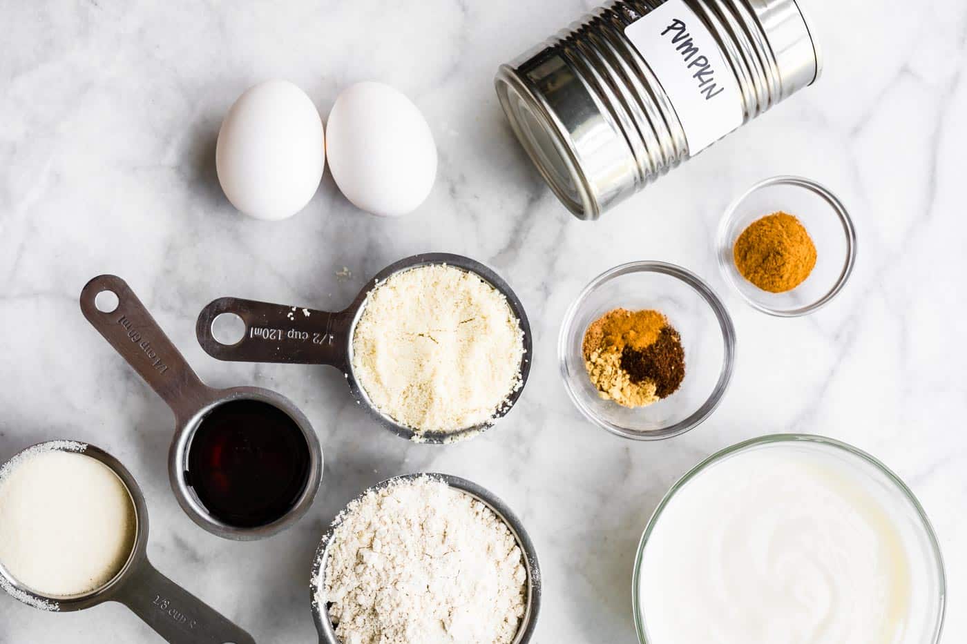 ingredients for gluten free pumpkin bars - eggs, spices, canned pumpkin, maple syrup, and gluten free flours