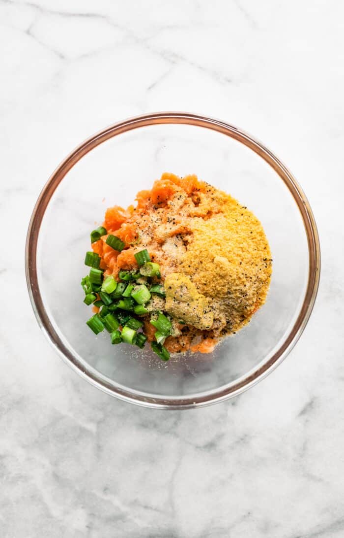 Overhead photo of chopped salmon, green onions, and panko in a glass bowl.