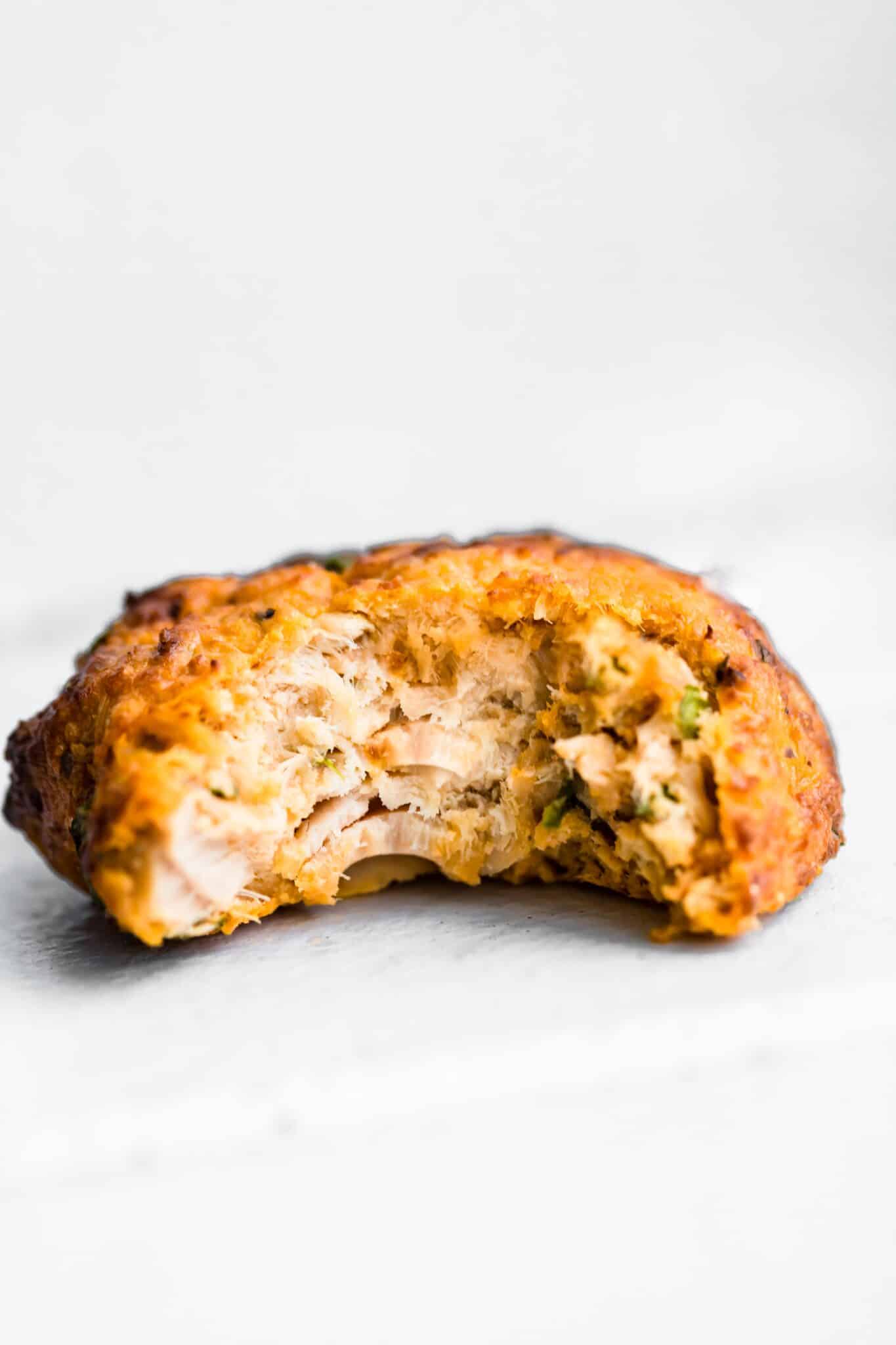 Side shot of a tuna patty with a bite taken out of it.