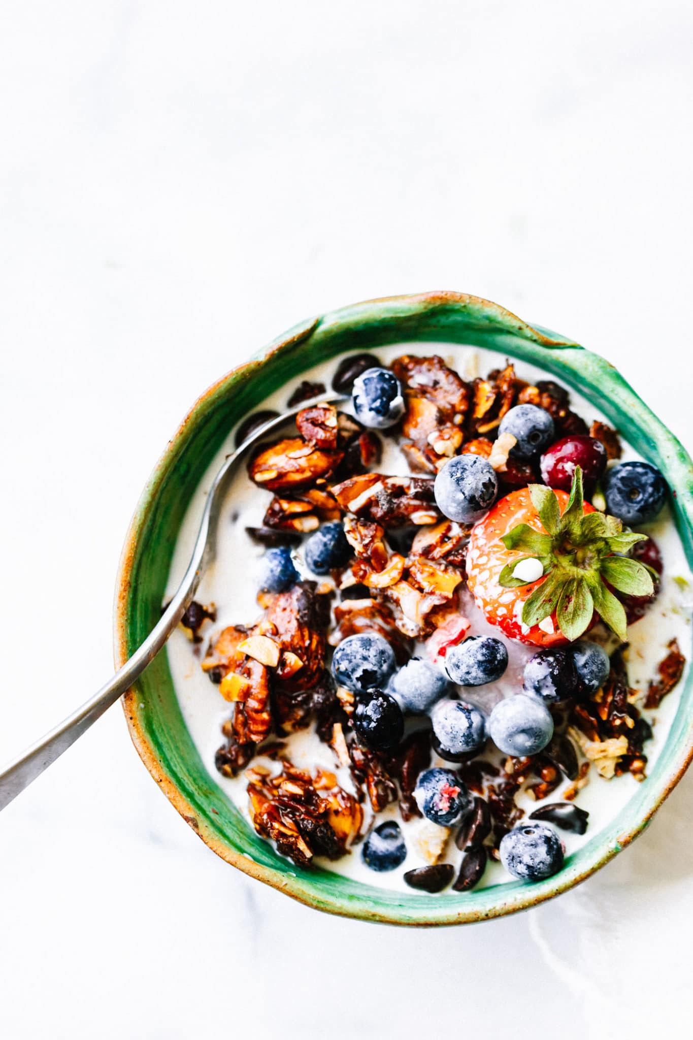 Grain free granola clusters in turquoise bowl with yogurt and fresh berries.