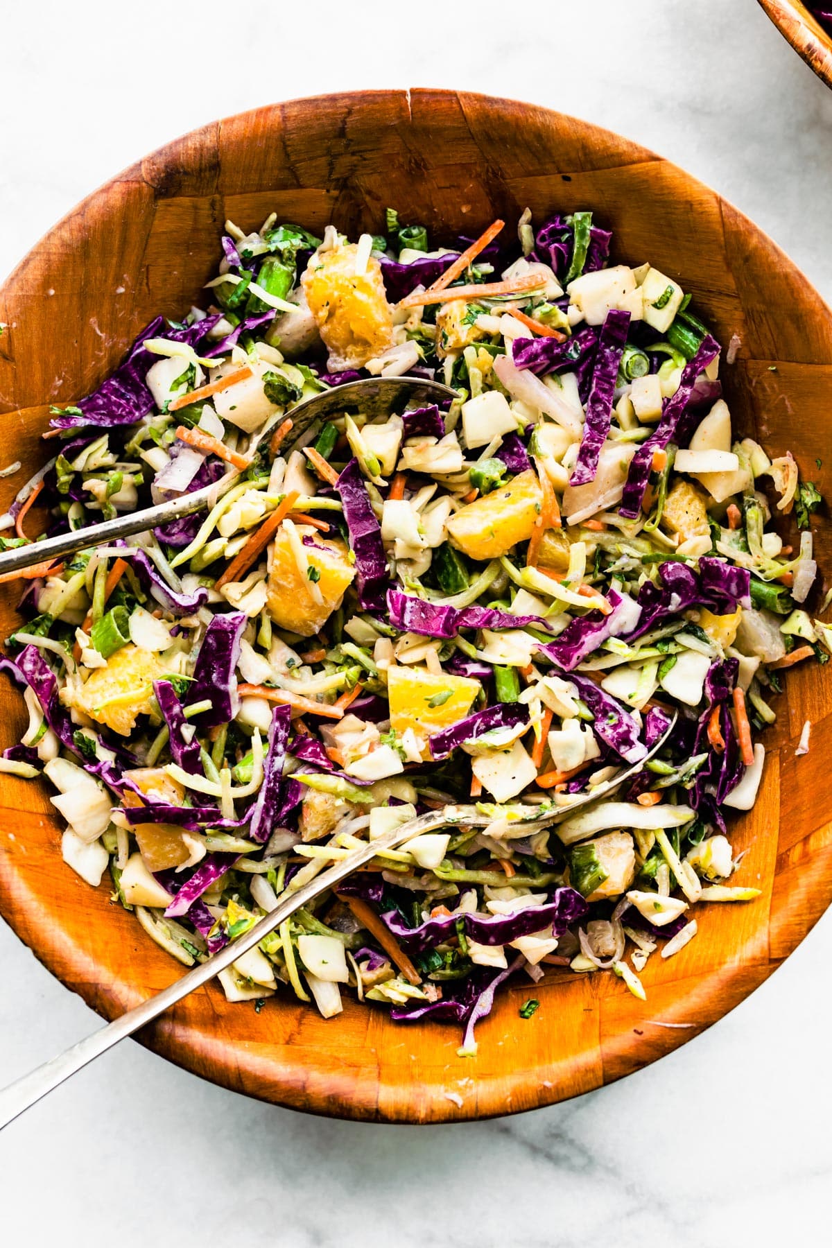Overhead image of a bowl of easy pineapple coleslaw with two serving spoons sticking out.