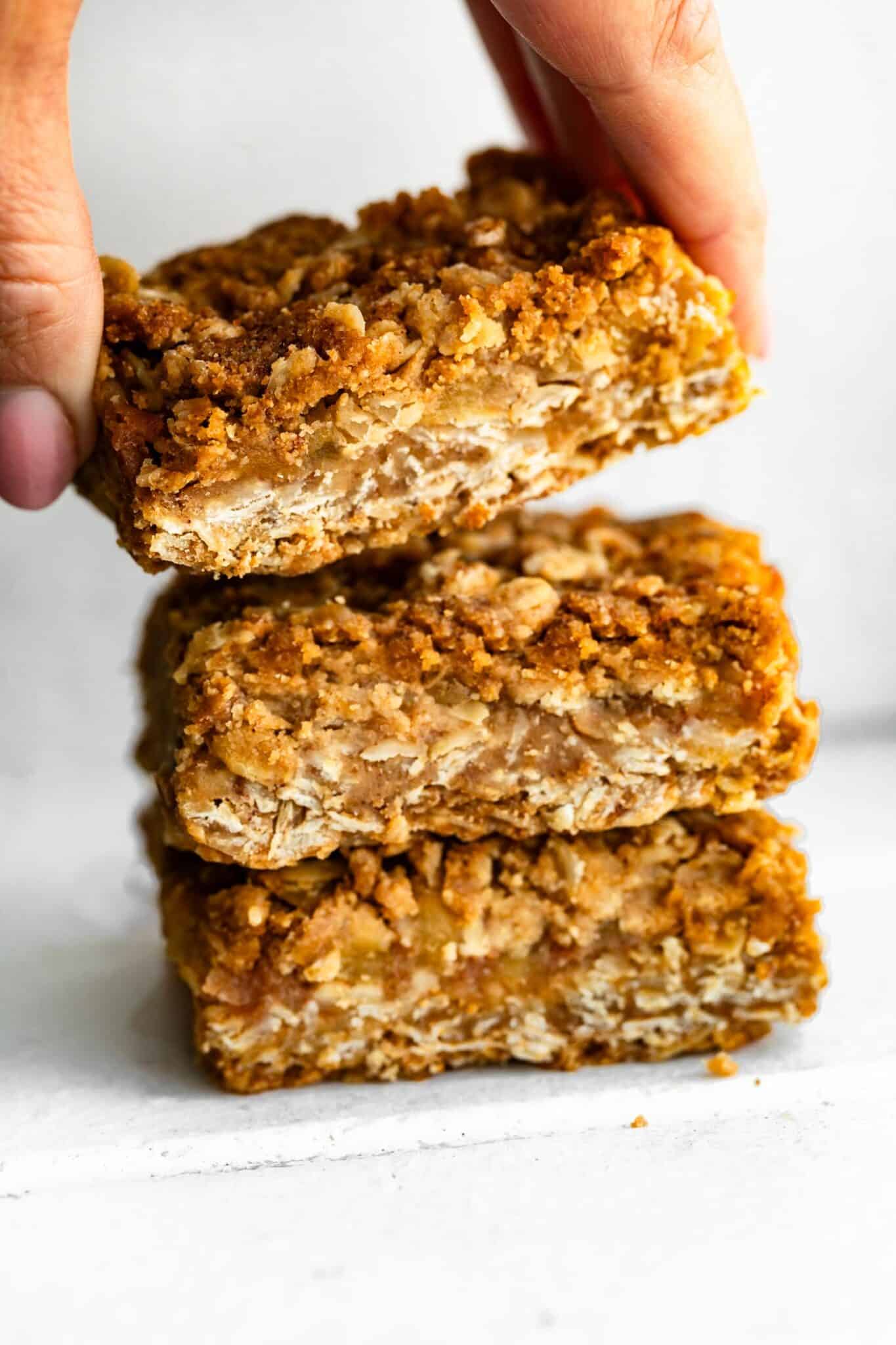 woman's hands grabbing an apple crisp bar of a stack of 3 bars