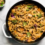 Overhead photo of one pot Thai peanut sauce noodles on a white marble countertop.
