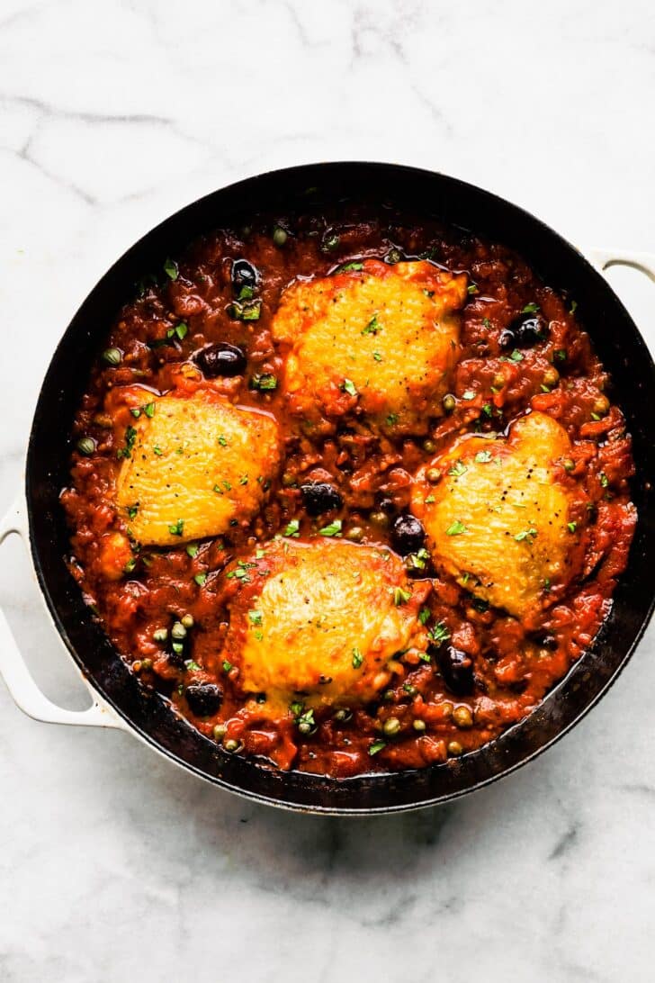 Overhead photo of Skillet Chicken Puttanesca recipe in a cast iron skillet.
