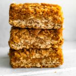 Stack of gluten-free apple crisp bars with golden oat crumble topping and spiced apple filling.