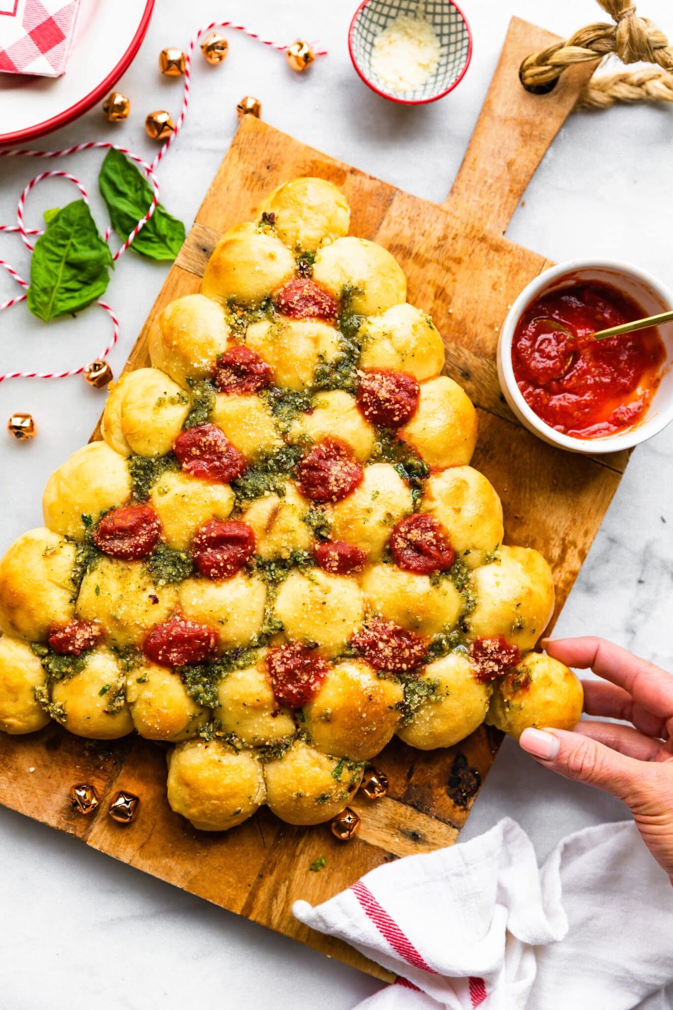 A woman's hand pulling a pizza dough ball from a gluten free Christmas tree.