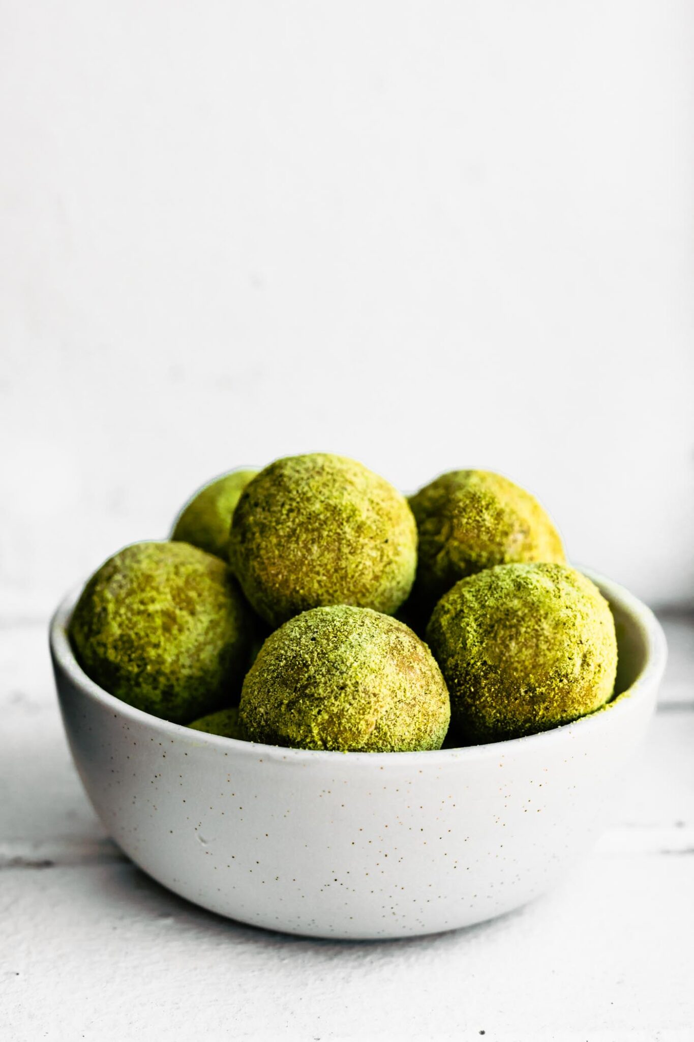 white bowl of green matcha protein bites