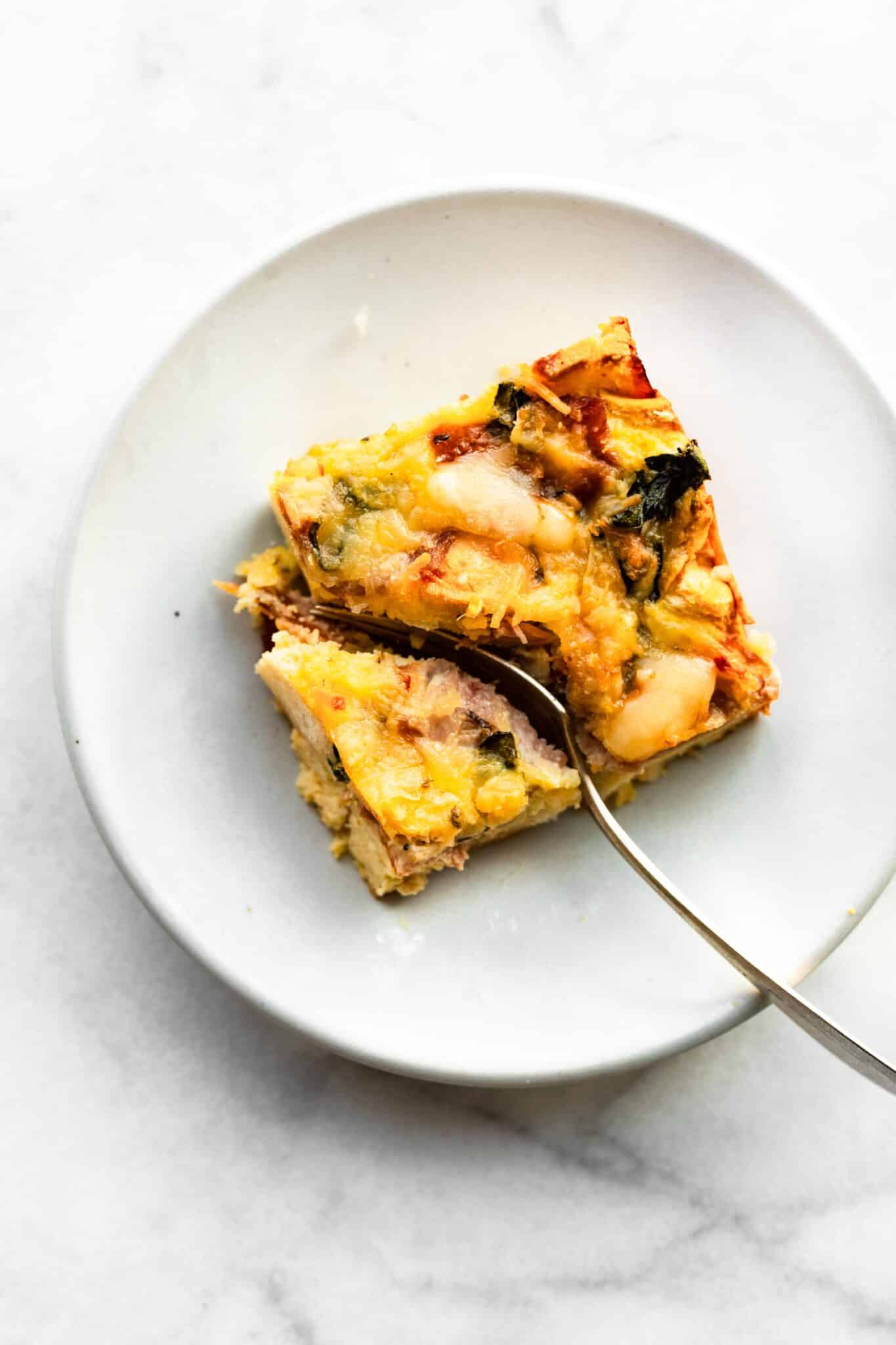 Overhead photo of a fork slicing through a piece of gluten free breakfast strata.