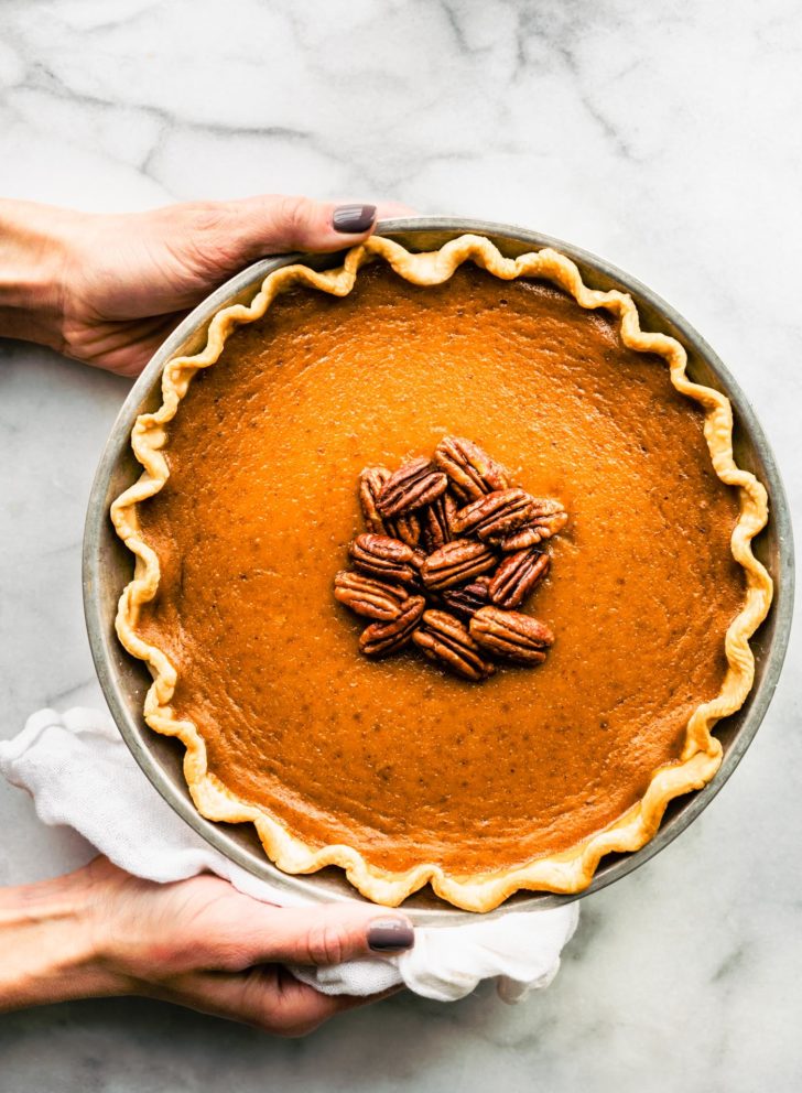 Two hands holding a gluten free pumpkin pie
