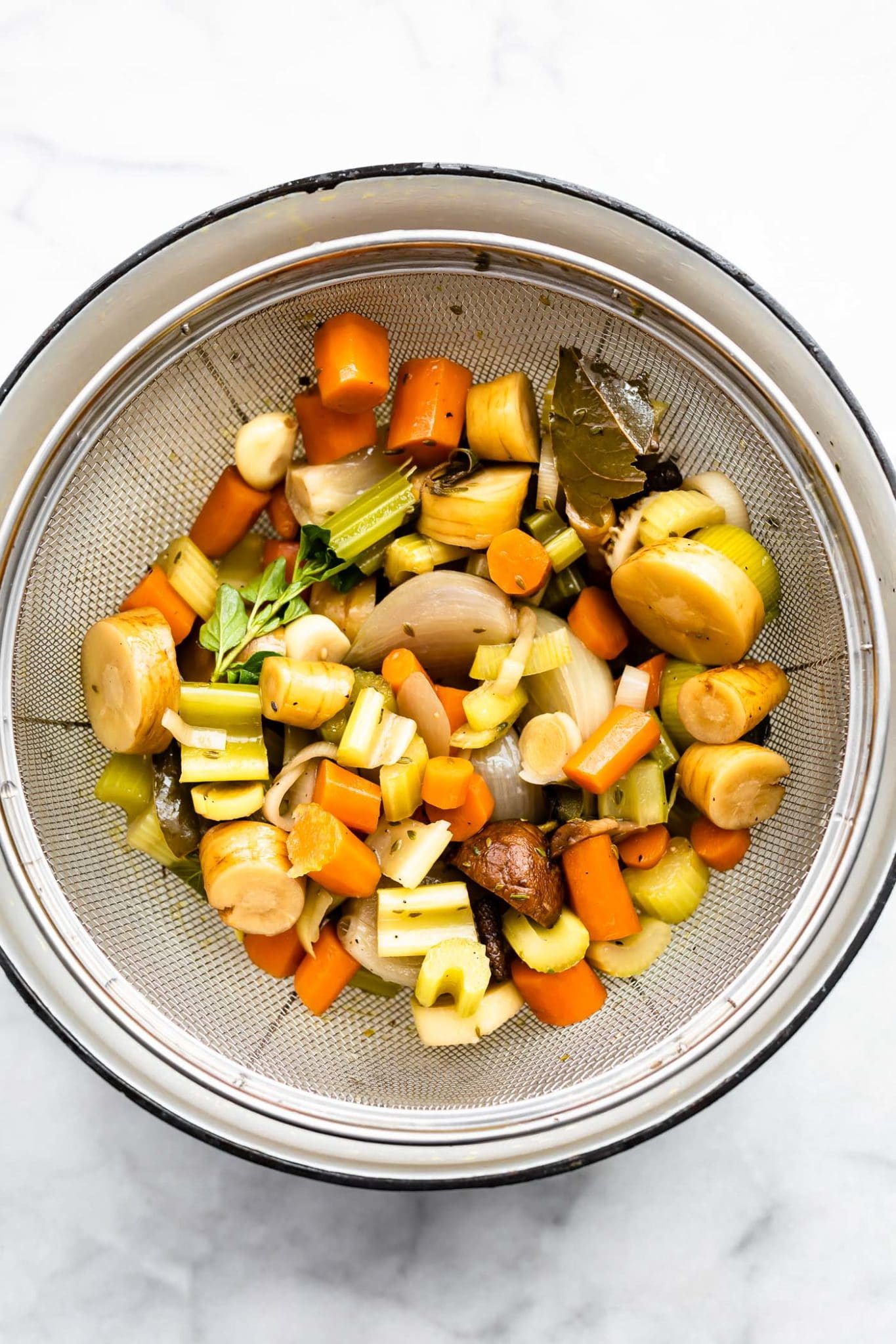 chopped vegetables being strained showing how to make vegetable broth.