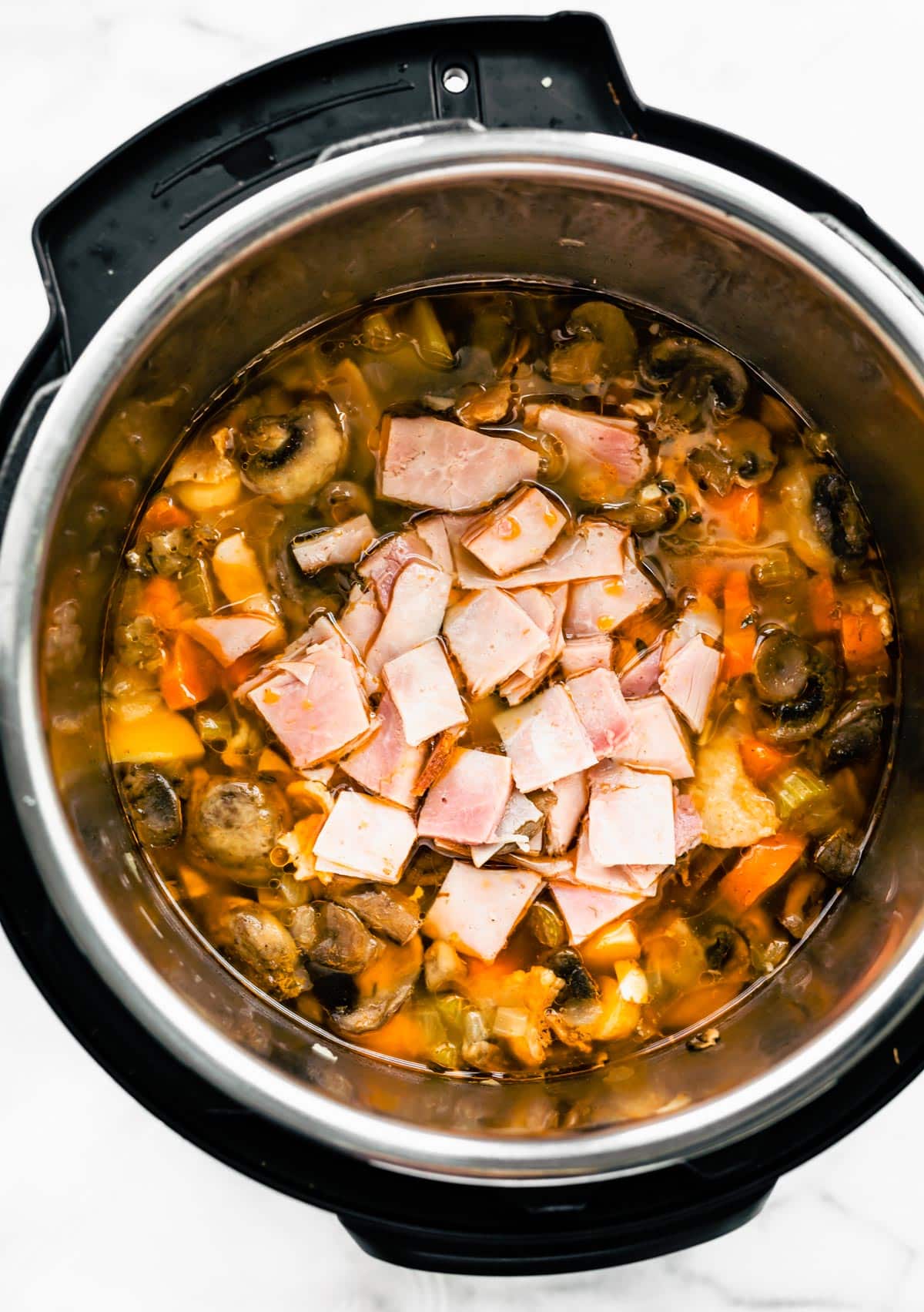 Diced ham and bacon on top of vegetable soup.