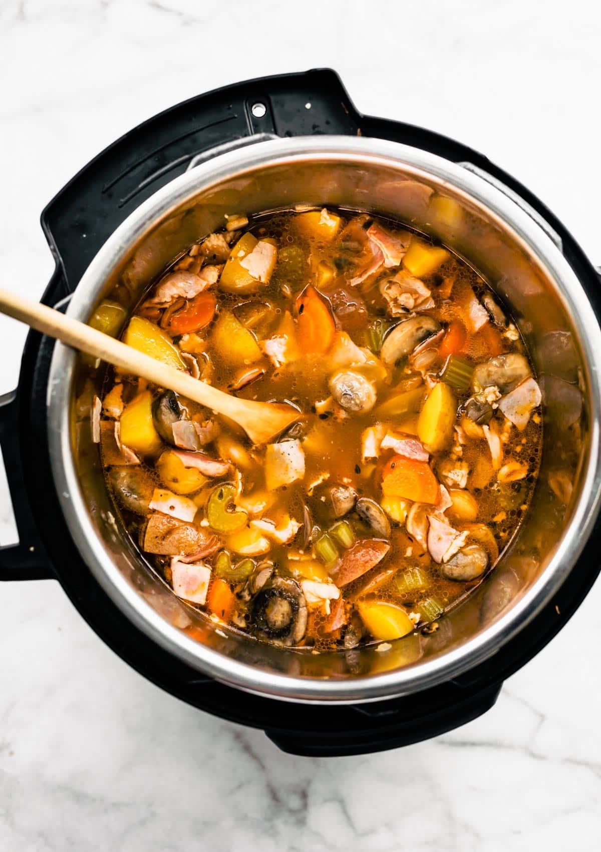 Cooked soup in an Instant Pot with a wooden spoon.