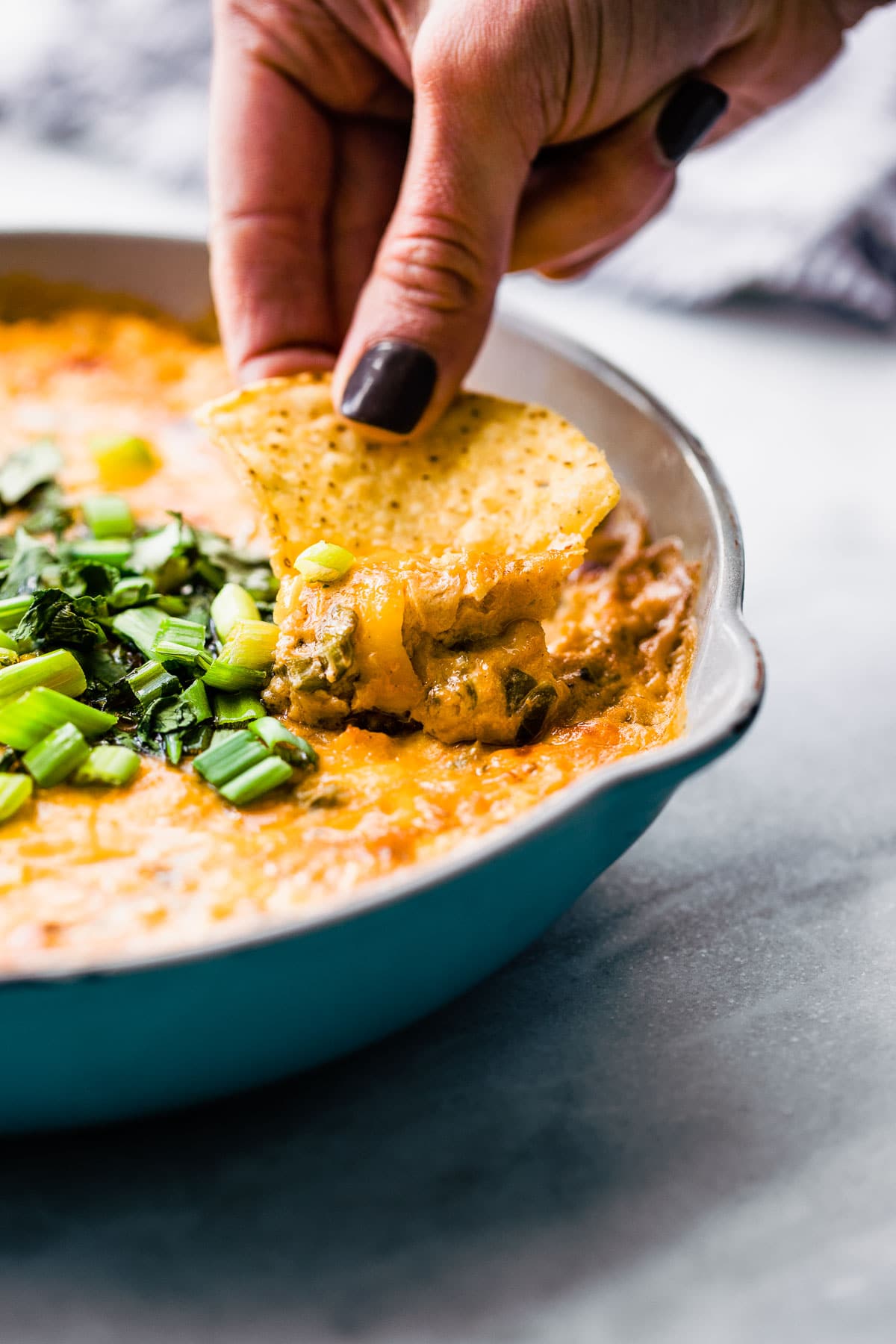 A tortilla chip scooping up roasted crab and cheese dip