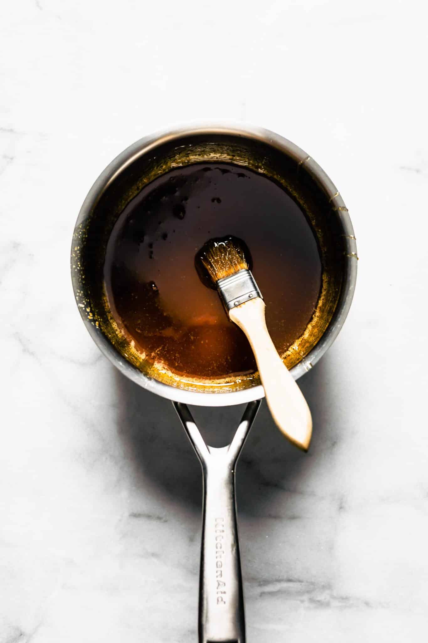 Overhead photo of a small soup pot with maple bourbon glaze with a brush.