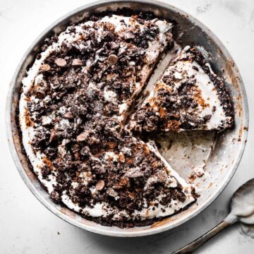 overhead image of vegan dirt pie in a pie tin with a piece missing and another piece sliced and ready to serve