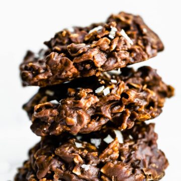 3 chocolate peanut butter cornflake cookies topped with coconut flakes and sea salt stacked on top of each other