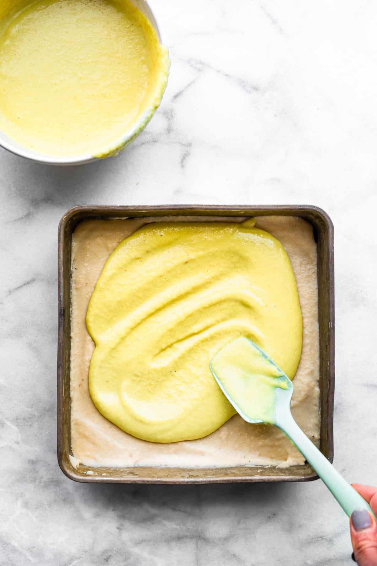 Lemon filling being spread onto cheesecake base.