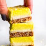 3 No Bake Lemon Cheesecake Bar pieces being stacked on top of one another.