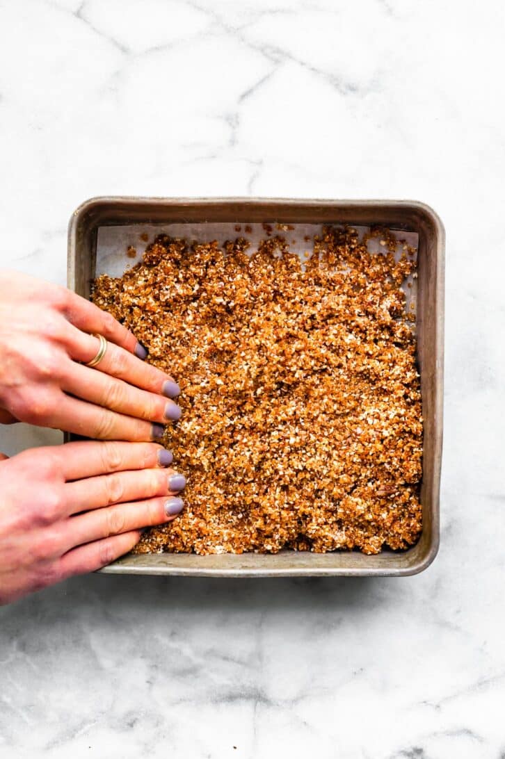 Cheesecake base being spread out into a pan.