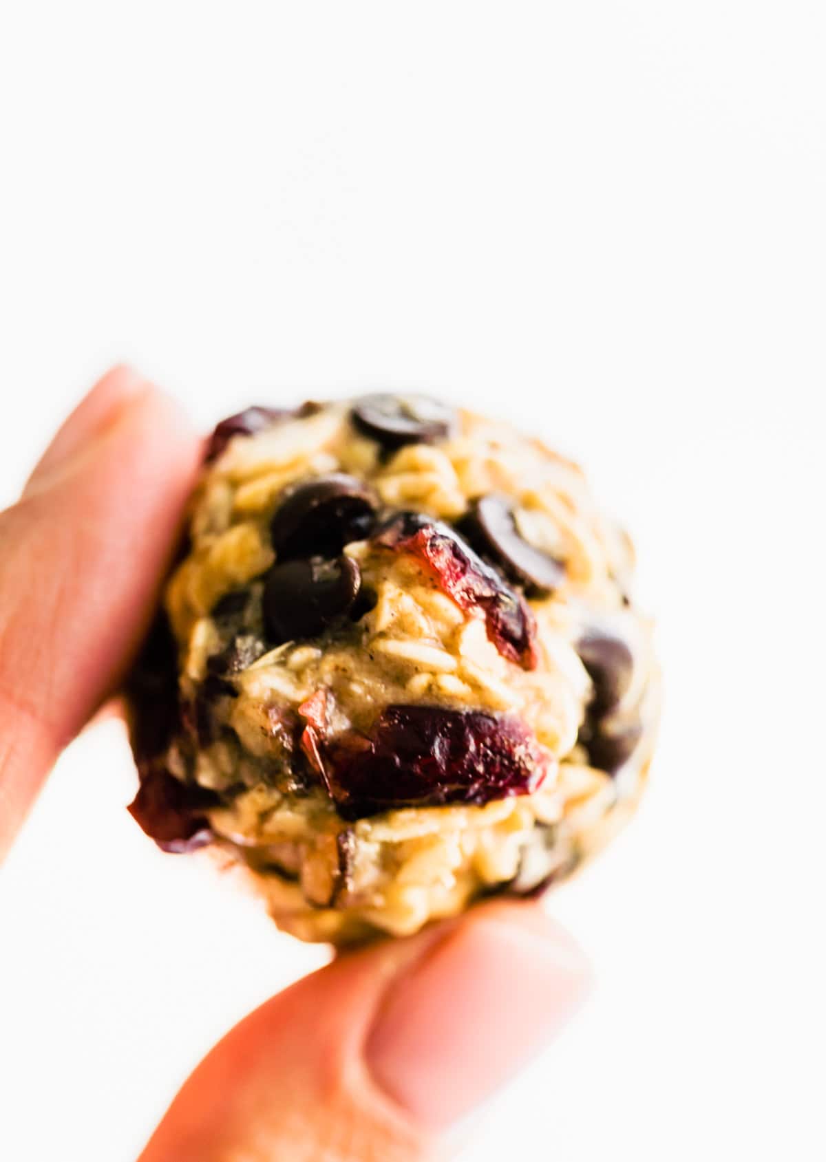 close up of hand holding chocolate chip oatmeal and cranberry oatmeal energy ball.
