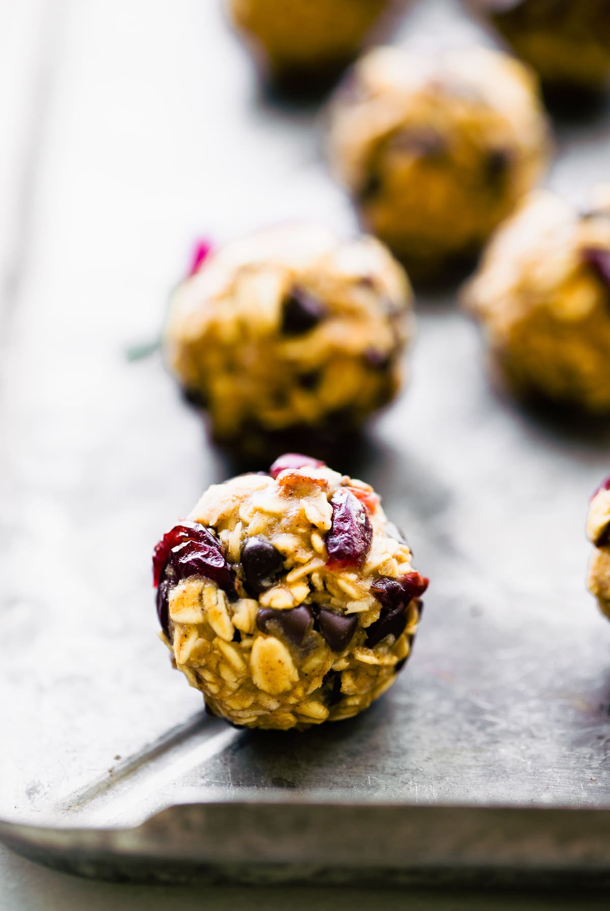 Close up view single oatmeal energy ball with dried cranberries and chocolate chips poking from bite.
