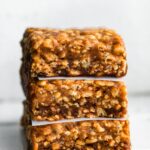 A stack of three homemade protein bars with wax paper between them.