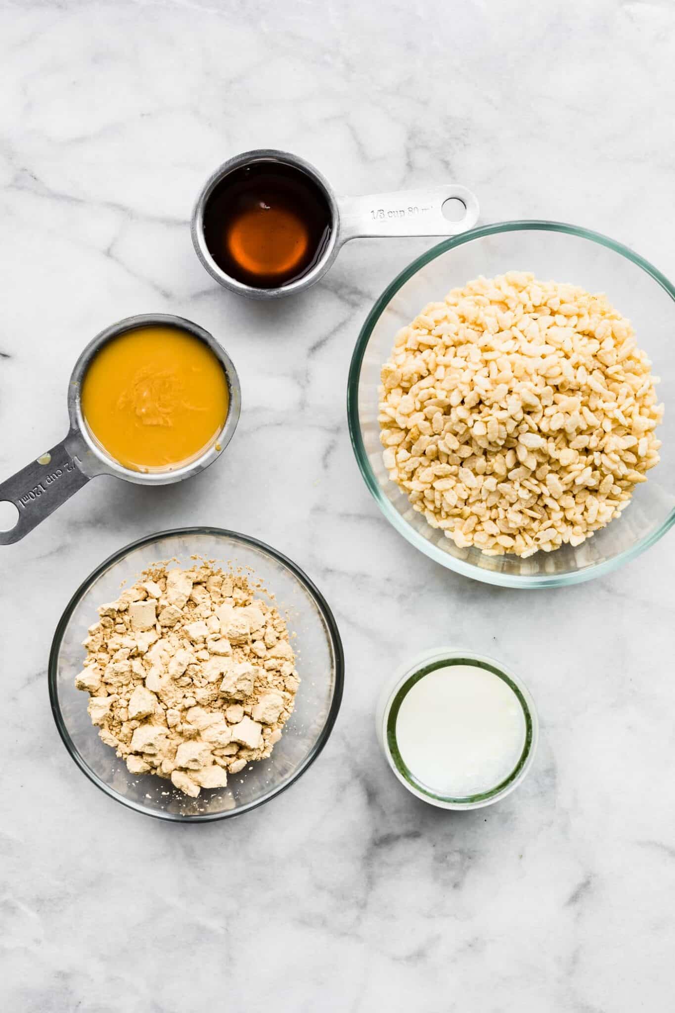 Ingredients for crispy peanut butter protein bars on a white marble countertop.
