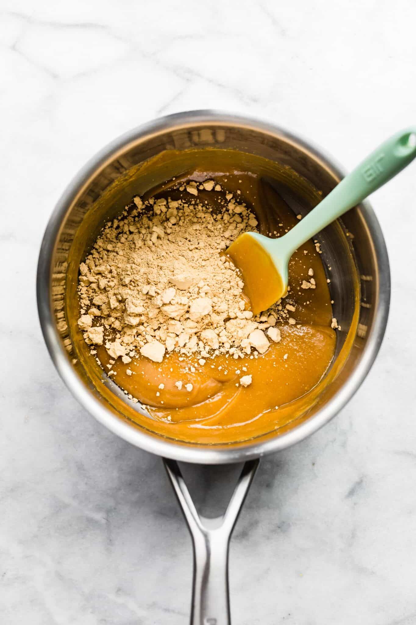 Vanilla protein powder on a mixture of peanut butter in a small pan.