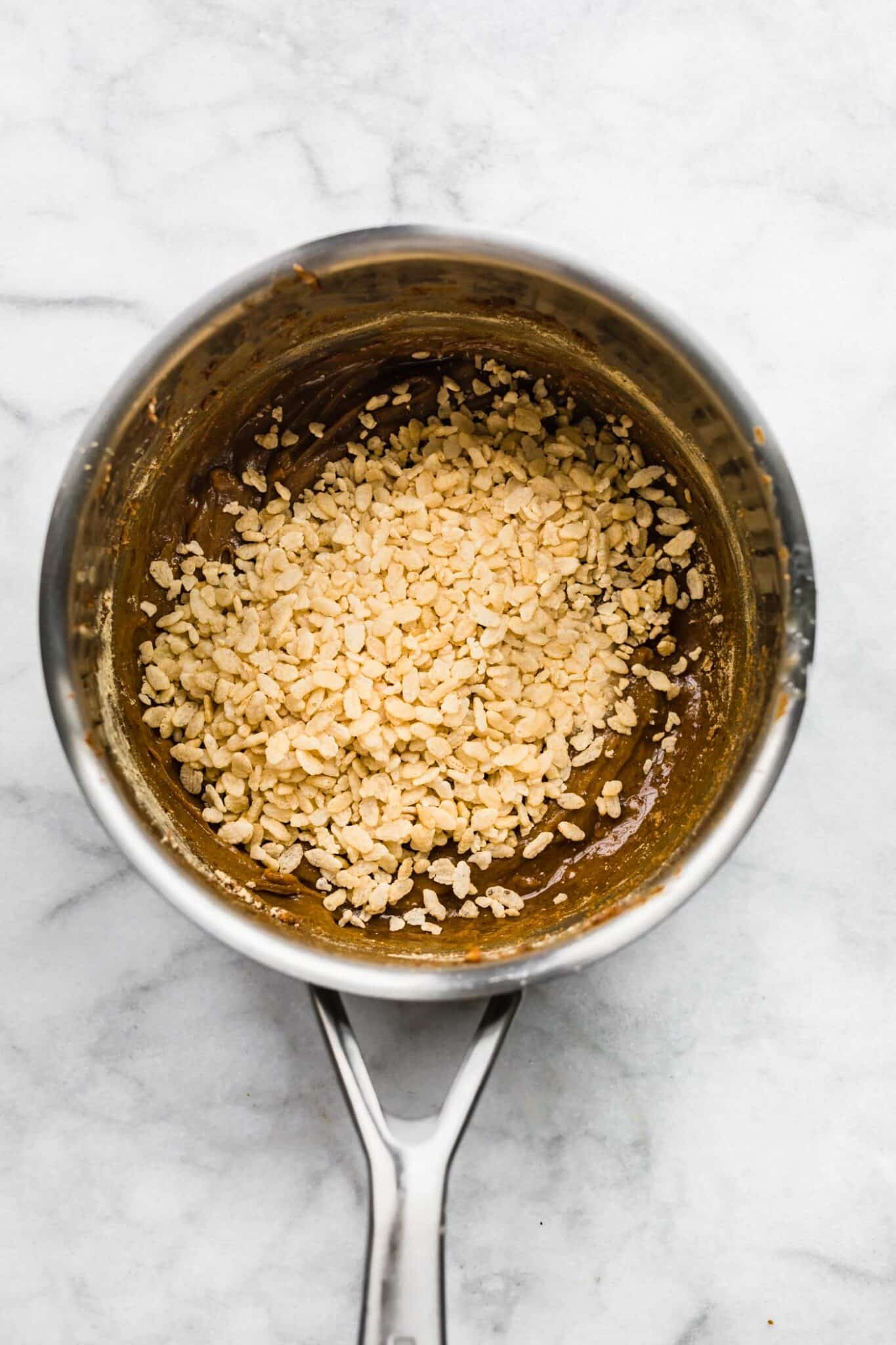 Crispy puffed rice cereal in a pot of peanut butter maple syrup mixture.