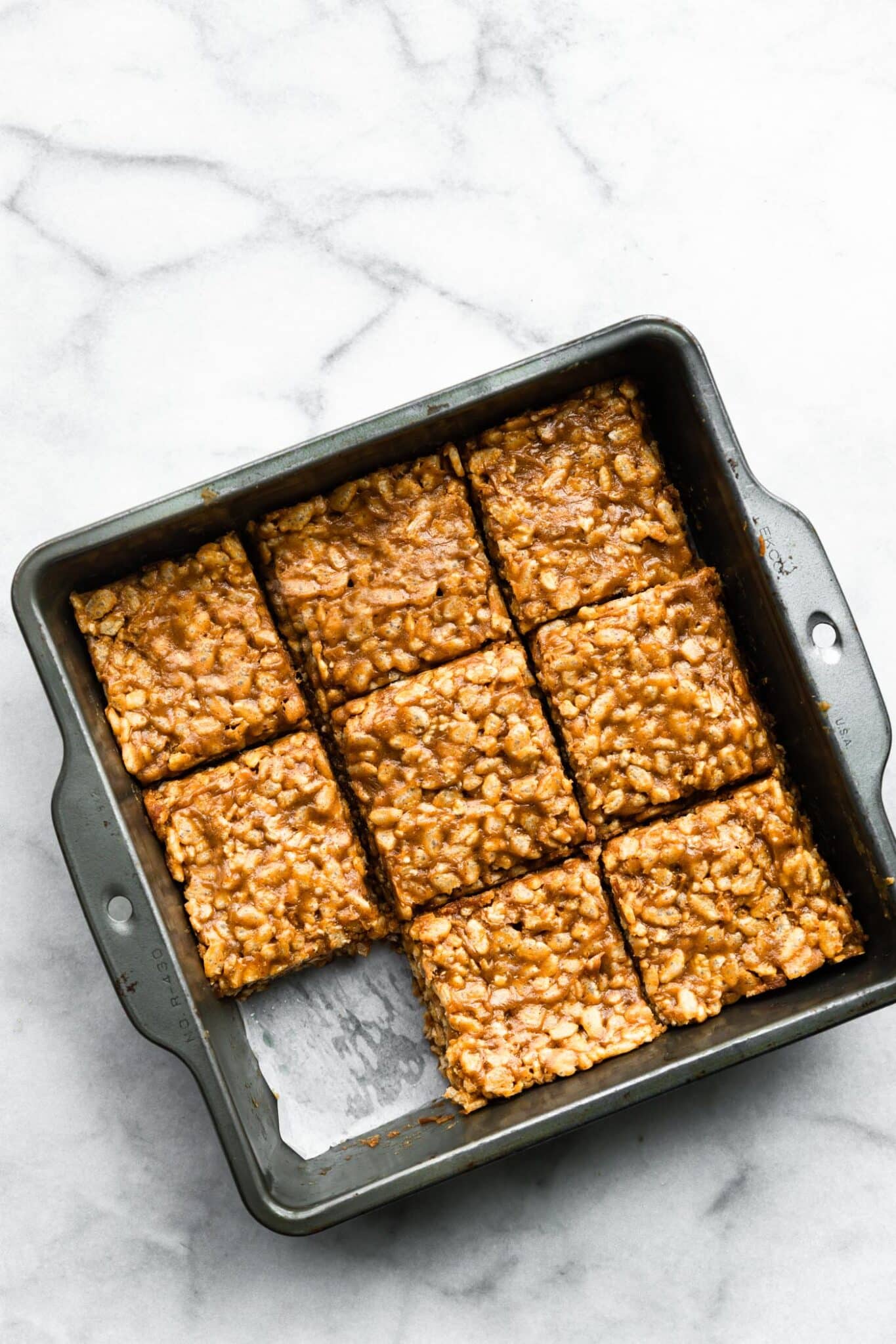 A pan of protein bars cut into nine pieces with one bar missing.