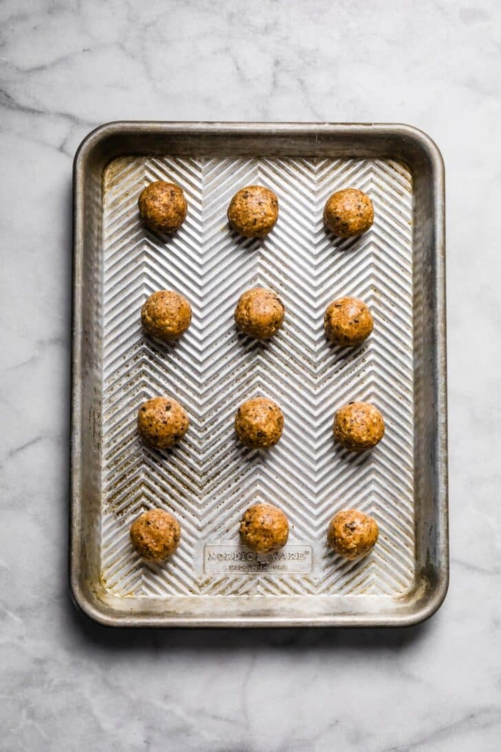 Uncoated pecan pie energy balls arranged evenly on a metal baking sheet.