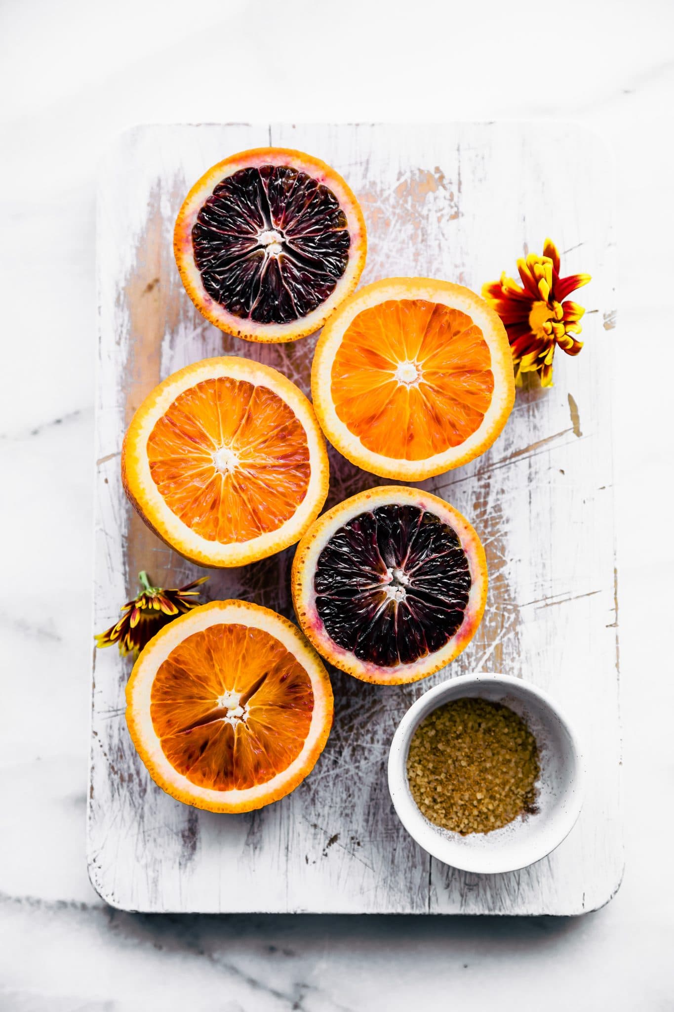 overhead image: blood oranges and navel oranges sliced in half on cutting board