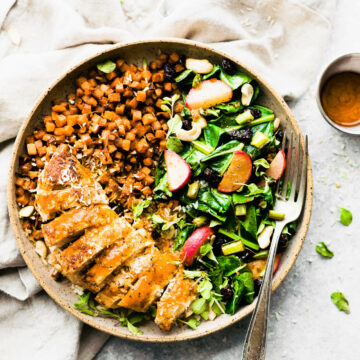 Overhead view stone bowl filled with jerk chicken breast, roasted sweet potatoes and side salad.