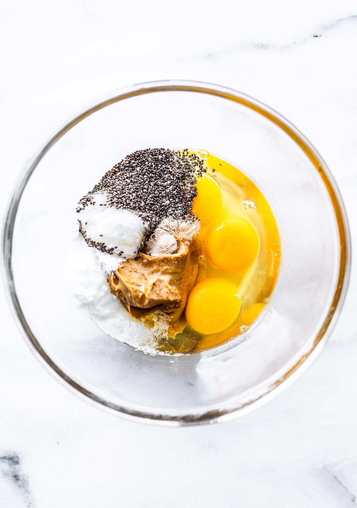 glass bowl with peanut butter, chia seeds, eggs, and baking powder to make low carb pancakes