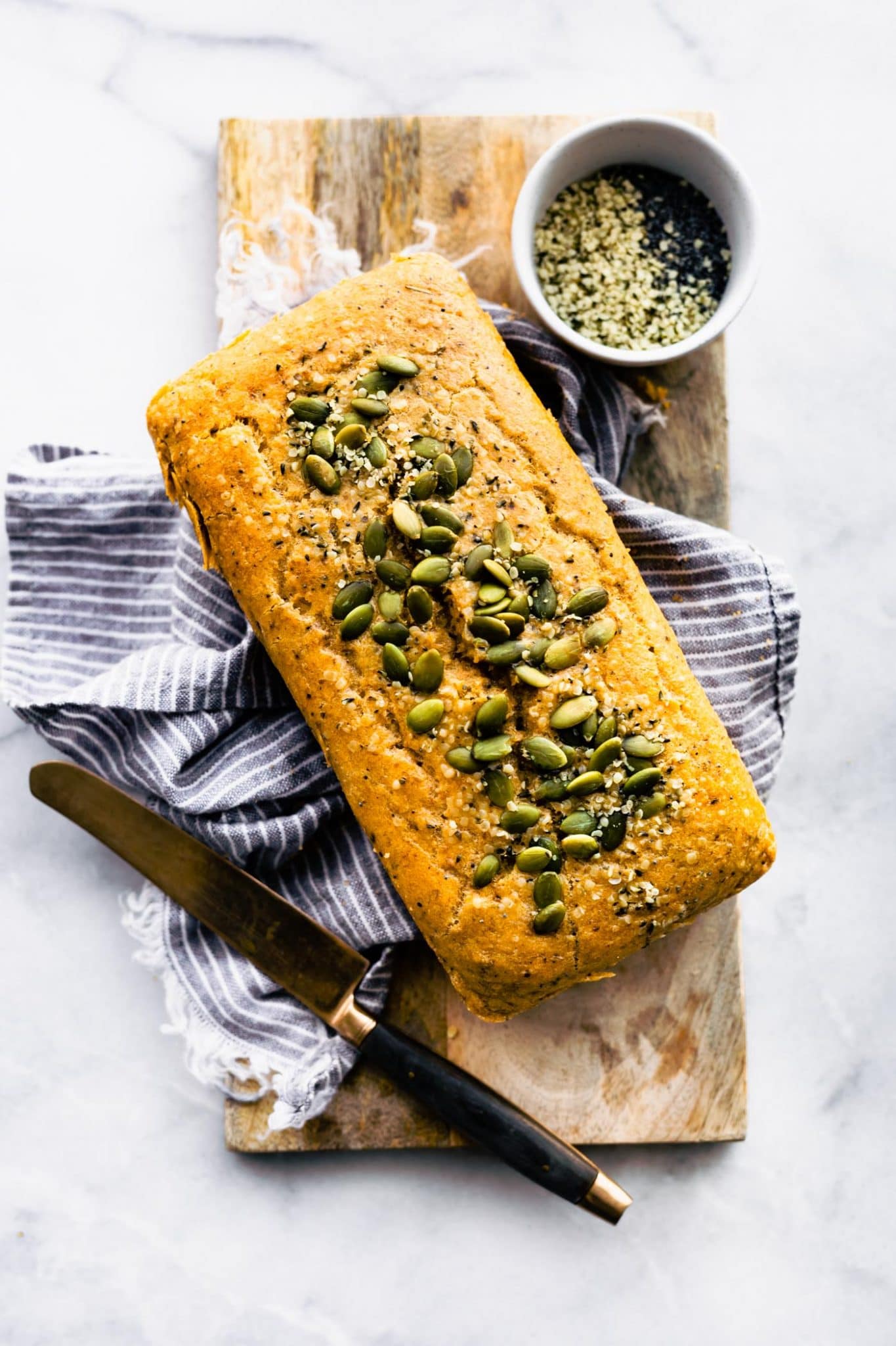 Overhead photo of a loaf of paleo bread on a towel and wooden cutting board.
