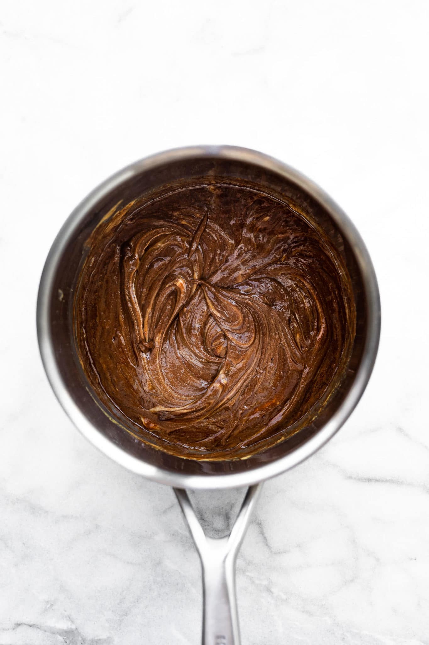 a saucepan filled with a melted mixture of chocolate, peanut butter, and honey for chocolate peanut butter cornflake cookies